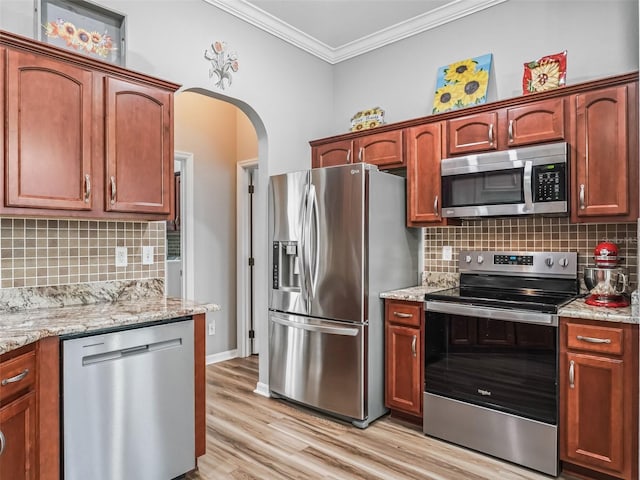 16863 SE 110th Court Rd, Summerfield, FL 34491 - kitchen featuring stainless steel appliances, arched walkways, crown molding, tasteful backsplash, and light wood-style floors