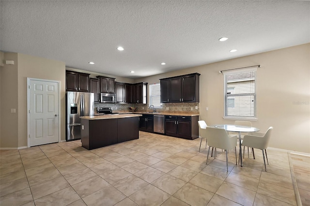 20945 Oldenburg Loop, Mount Dora, FL 32757 - kitchen featuring appliances with stainless steel finishes, light countertops, a center island, decorative backsplash, and light tile patterned floors