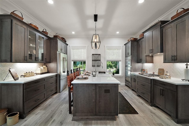 622 W 11th Ave, Mount Dora, FL 32757 - kitchen featuring stainless steel appliances, crown molding, light countertops, decorative backsplash, and a kitchen island with sink