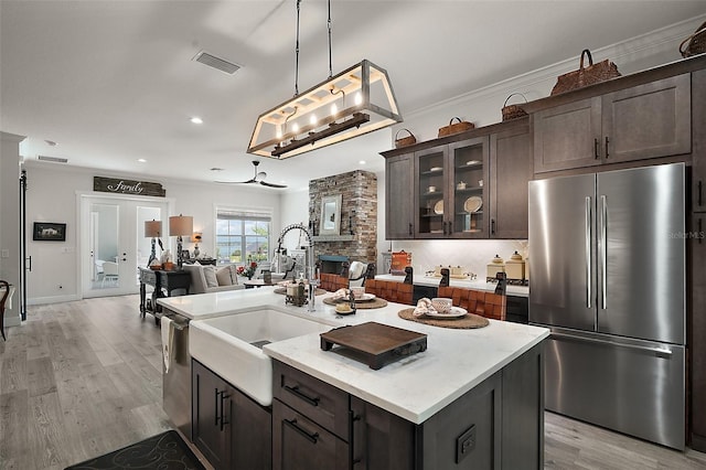 622 W 11th Ave, Mount Dora, FL 32757 - kitchen featuring appliances with stainless steel finishes, dark brown cabinetry, open floor plan, light wood finished floors, and a kitchen island with sink