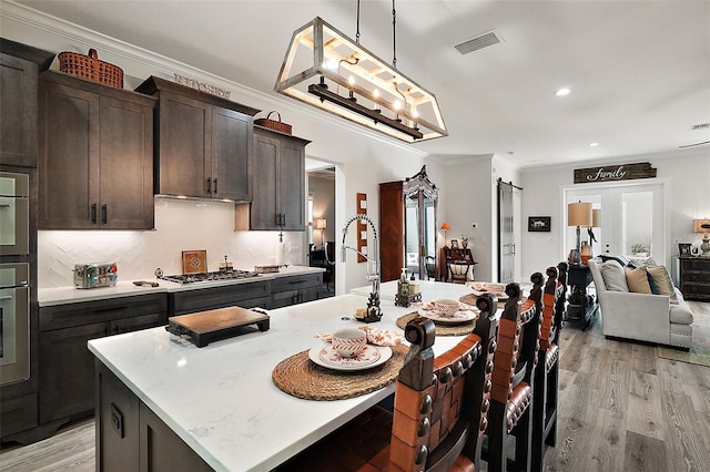 622 W 11th Ave, Mount Dora, FL 32757 - kitchen featuring ornamental molding, light countertops, light wood-type flooring, an island with sink, and open floor plan