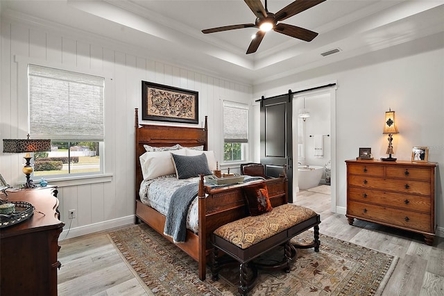 622 W 11th Ave, Mount Dora, FL 32757 - bedroom with a tray ceiling, light wood-style flooring, crown molding, a barn door, and ensuite bathroom