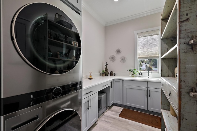 622 W 11th Ave, Mount Dora, FL 32757 - laundry area with stacked washer and clothes dryer, crown molding, light wood finished floors, and cabinet space