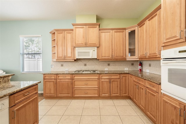 4548 Barrister Dr, Clermont, FL 34711 - kitchen featuring white appliances, decorative backsplash, stone counters, light tile patterned floors, and glass insert cabinets