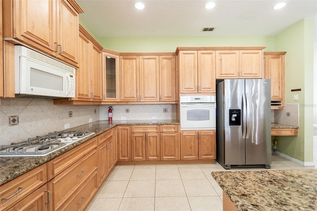 4548 Barrister Dr, Clermont, FL 34711 - kitchen featuring white appliances, recessed lighting, light tile patterned floors, dark stone countertops, and backsplash