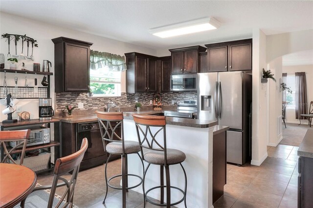 6906 Glenbrook Dr, Lakeland, FL 33811 - kitchen featuring stainless steel appliances, dark brown cabinetry, tasteful backsplash, and arched walkways