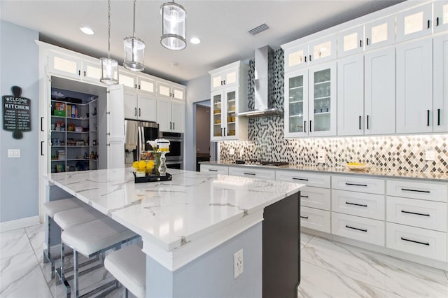 1702 Hidden Palms Dr, Davenport, FL 33897 - kitchen featuring light marble finish floors, a kitchen island, backsplash, wall chimney exhaust hood, and recessed lighting