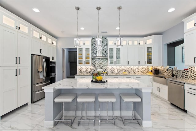 1702 Hidden Palms Dr, Davenport, FL 33897 - kitchen featuring appliances with stainless steel finishes, light marble finish floors, a kitchen island, a breakfast bar, and decorative backsplash