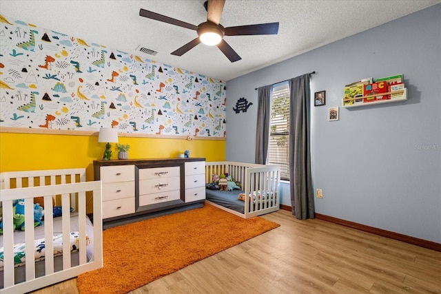 3184 Maltby Dr, Deltona, FL 32738 - bedroom featuring light wood-style floors, a textured ceiling, a nursery area, and a ceiling fan