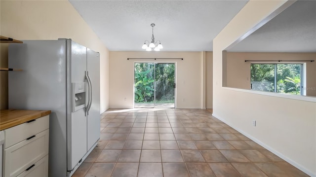 15925 Summit Ct, Clermont, FL 34711 - kitchen featuring white fridge with ice dispenser, a chandelier, white cabinets, hanging light fixtures, and light tile patterned floors