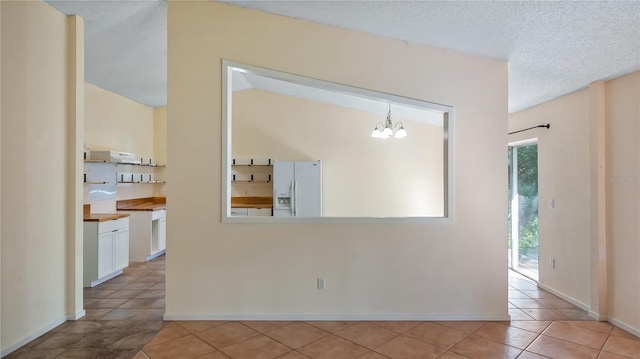 15925 Summit Ct, Clermont, FL 34711 - empty room featuring light tile patterned floors, a chandelier, and a textured ceiling