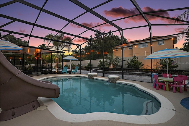 318 Stone Castle Loop, Lady Lake, FL 32159 - pool at dusk featuring a patio area, a water slide, and a lanai
