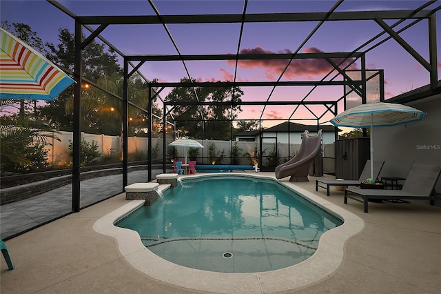 318 Stone Castle Loop, Lady Lake, FL 32159 - pool at dusk with a water slide, a patio, a fenced backyard, and glass enclosure