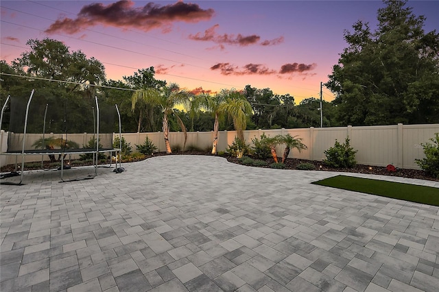 318 Stone Castle Loop, Lady Lake, FL 32159 - patio terrace at dusk featuring a patio area, a fenced backyard, and a trampoline