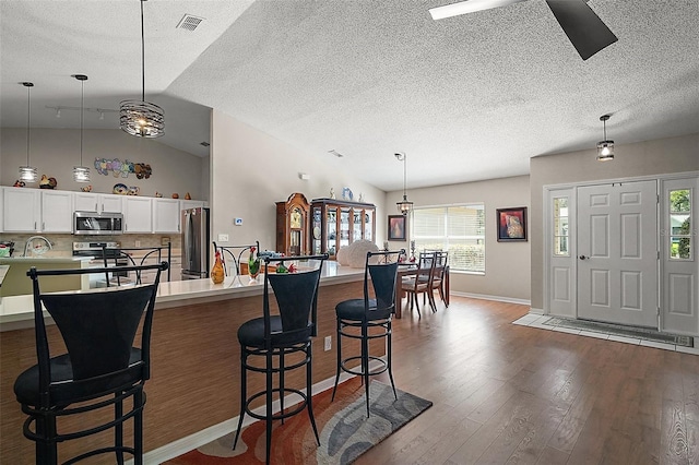4300 Leafway Cir, Leesburg, FL 34748 - kitchen with stainless steel appliances, wood finished floors, a breakfast bar, light countertops, and decorative light fixtures