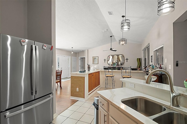 4300 Leafway Cir, Leesburg, FL 34748 - kitchen featuring freestanding refrigerator, vaulted ceiling, light tile patterned floors, pendant lighting, and a textured ceiling