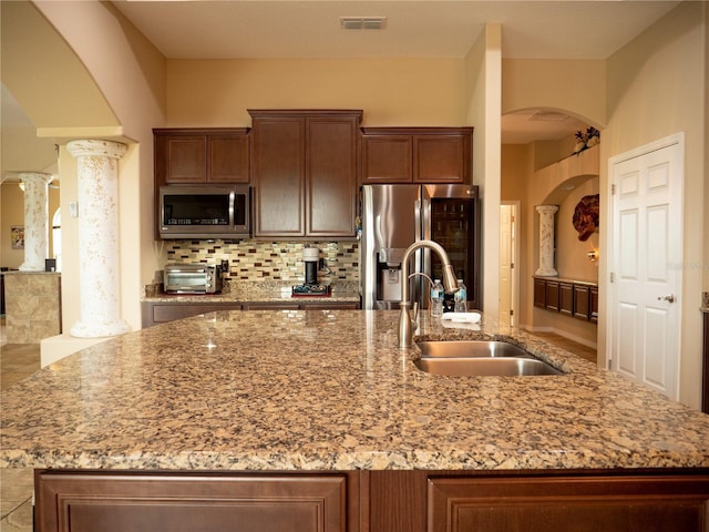 29222 Can Do Ln, Tavares, FL 32778 - kitchen with appliances with stainless steel finishes, a kitchen island with sink, arched walkways, and tasteful backsplash