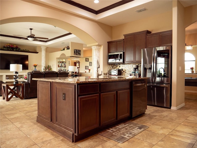 29222 Can Do Ln, Tavares, FL 32778 - kitchen featuring stainless steel appliances, a raised ceiling, arched walkways, a kitchen island with sink, and ornamental molding
