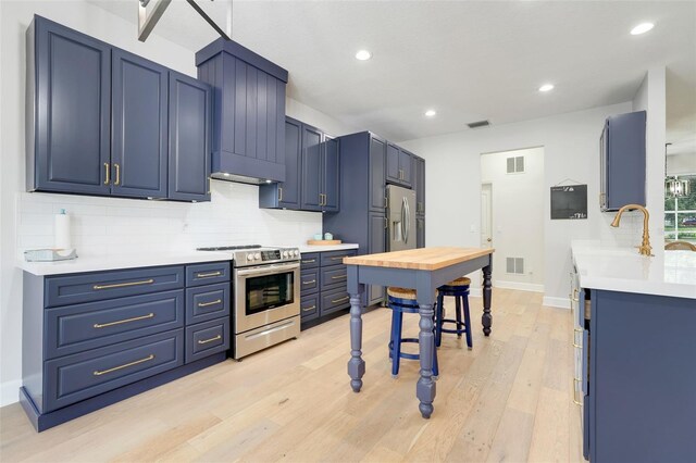 15629 Catherine Cir, Groveland, FL 34736 - kitchen featuring appliances with stainless steel finishes, blue cabinets, backsplash, light wood finished floors, and light countertops