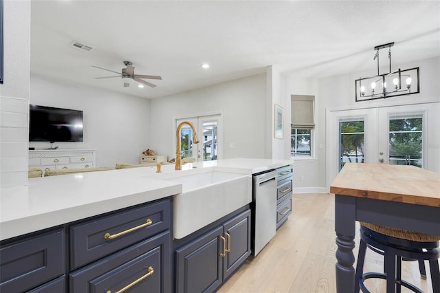 15629 Catherine Cir, Groveland, FL 34736 - kitchen with french doors, stainless steel dishwasher, light wood finished floors, a ceiling fan, and pendant lighting
