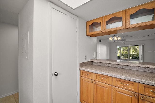 101 N Grandview St Unit 103, Mount Dora, FL 32757 - kitchen with glass insert cabinets, light countertops, brown cabinetry, and a chandelier