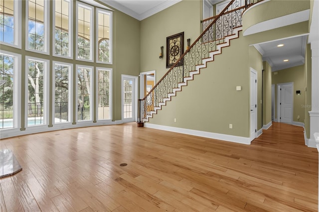 1325 Otters View Ct, Fruitland Park, FL 34731 - unfurnished living room with a high ceiling, crown molding, plenty of natural light, stairs, and light wood-style floors