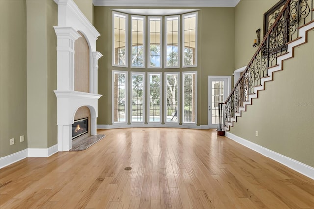 1325 Otters View Ct, Fruitland Park, FL 34731 - unfurnished living room with a high end fireplace, light wood finished floors, stairway, and a towering ceiling