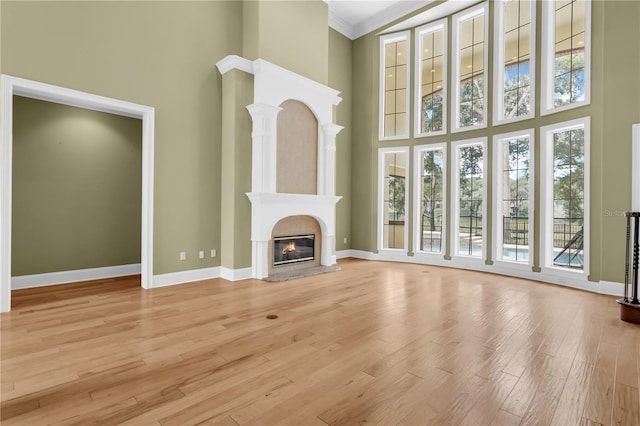 1325 Otters View Ct, Fruitland Park, FL 34731 - unfurnished living room featuring a towering ceiling, a fireplace, light wood-style flooring, and crown molding
