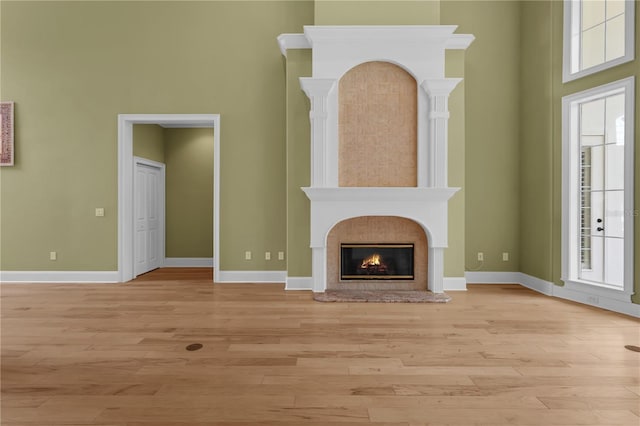 1325 Otters View Ct, Fruitland Park, FL 34731 - unfurnished living room featuring light wood-type flooring, a premium fireplace, and a high ceiling