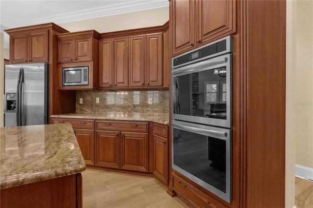 1325 Otters View Ct, Fruitland Park, FL 34731 - kitchen featuring appliances with stainless steel finishes, brown cabinets, decorative backsplash, light wood finished floors, and light stone counters