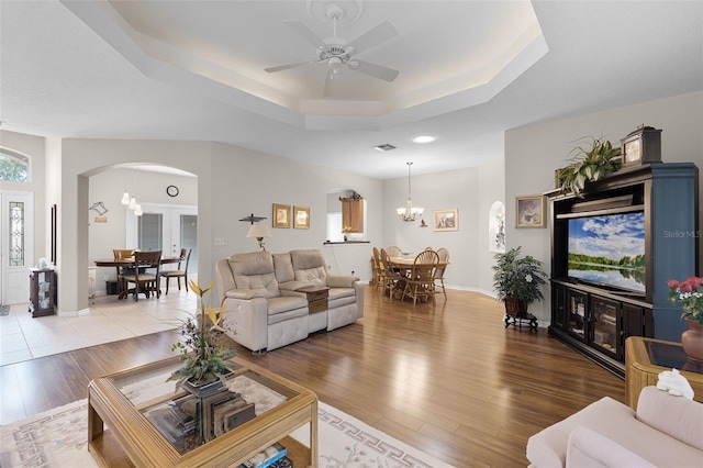 5620 Illumination Ln, Leesburg, FL 34748 - living room with arched walkways, a raised ceiling, a chandelier, wood finished floors, and ceiling fan