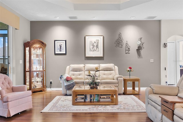 5620 Illumination Ln, Leesburg, FL 34748 - living room featuring wood finished floors, recessed lighting, arched walkways, and a tray ceiling
