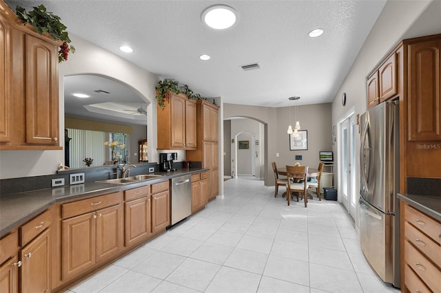 5620 Illumination Ln, Leesburg, FL 34748 - kitchen with stainless steel appliances, arched walkways, light tile patterned flooring, dark countertops, and a ceiling fan