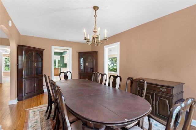 9223 Silver Lake Dr, Leesburg, FL 34788 - dining room with a chandelier, arched walkways, healthy amount of natural light, and light wood finished floors