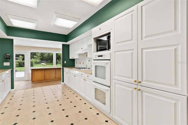 9223 Silver Lake Dr, Leesburg, FL 34788 - kitchen with white appliances, white cabinets, light countertops, backsplash, and light tile patterned flooring