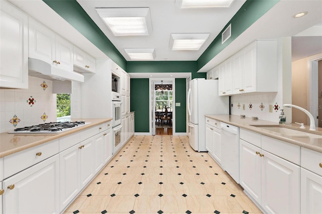 9223 Silver Lake Dr, Leesburg, FL 34788 - kitchen with white appliances, under cabinet range hood, white cabinets, light countertops, and backsplash