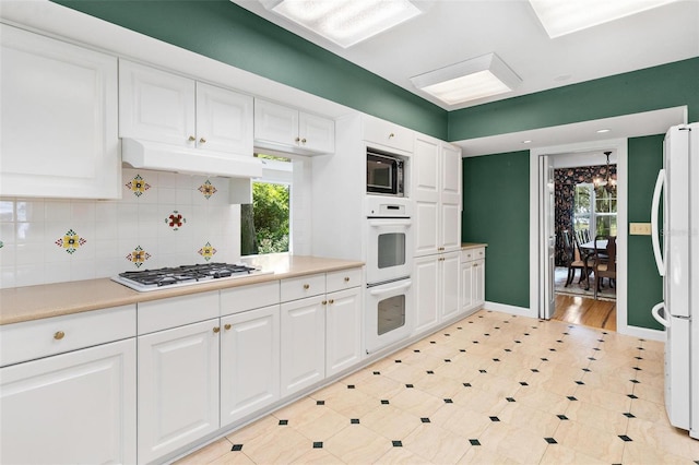 9223 Silver Lake Dr, Leesburg, FL 34788 - kitchen with white appliances, healthy amount of natural light, and white cabinetry