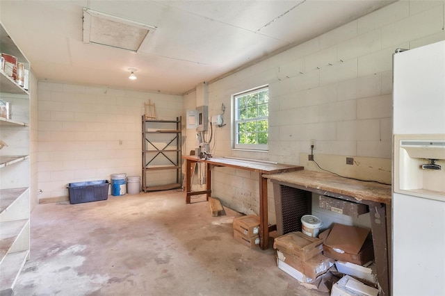 9223 Silver Lake Dr, Leesburg, FL 34788 - below grade area featuring white fridge with ice dispenser, a workshop area, and concrete block wall