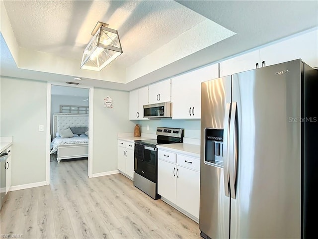 3723 Toulouse Ct, Punta Gorda, FL 33950 - kitchen with appliances with stainless steel finishes, light wood-style flooring, light countertops, white cabinets, and a textured ceiling