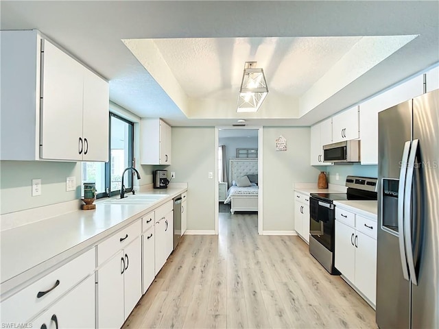 3723 Toulouse Ct, Punta Gorda, FL 33950 - kitchen with stainless steel appliances, a raised ceiling, light countertops, white cabinets, and light wood-style floors