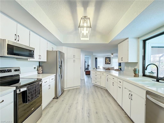3723 Toulouse Ct, Punta Gorda, FL 33950 - kitchen with appliances with stainless steel finishes, a textured ceiling, light countertops, light wood-style floors, and white cabinets