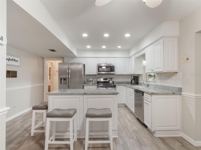 5556 Round Lake Rd, Apopka, FL 32712 - kitchen featuring stainless steel appliances, light wood finished floors, white cabinetry, light stone counters, and recessed lighting
