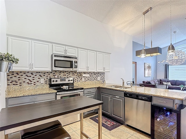 167 Castaway Beach Way, Kissimmee, FL 34746 - kitchen with appliances with stainless steel finishes, a peninsula, backsplash, a textured ceiling, and light tile patterned flooring