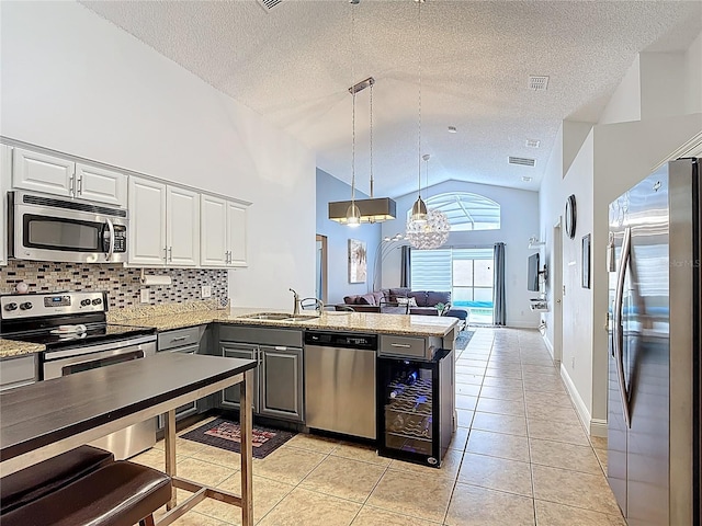 167 Castaway Beach Way, Kissimmee, FL 34746 - kitchen featuring appliances with stainless steel finishes, lofted ceiling, a peninsula, open floor plan, and a textured ceiling