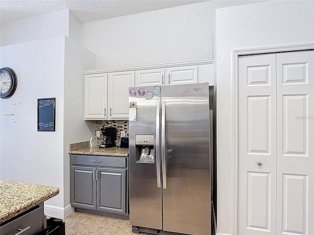167 Castaway Beach Way, Kissimmee, FL 34746 - kitchen with stainless steel fridge with ice dispenser, light stone countertops, tasteful backsplash, white cabinetry, and light tile patterned floors