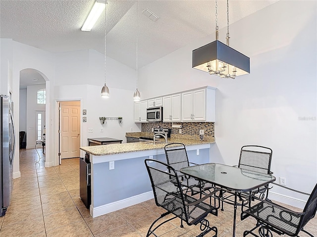167 Castaway Beach Way, Kissimmee, FL 34746 - kitchen featuring stainless steel microwave, range, arched walkways, a peninsula, and decorative backsplash
