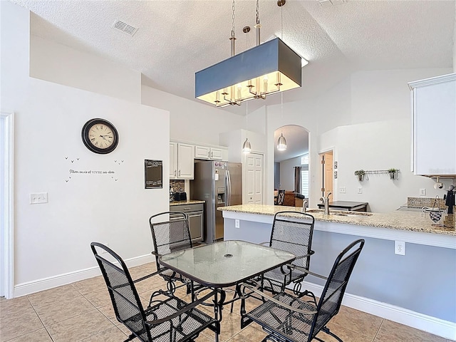 167 Castaway Beach Way, Kissimmee, FL 34746 - dining room featuring arched walkways, light tile patterned floors, a textured ceiling, high vaulted ceiling, and a chandelier