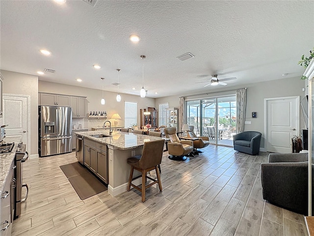 655 Conservation Blvd, Groveland, FL 34736 - kitchen featuring appliances with stainless steel finishes, gray cabinets, open floor plan, wood finish floors, and recessed lighting