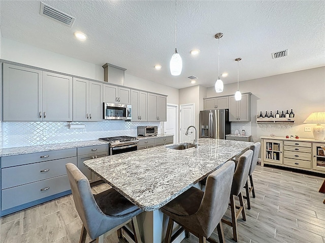 655 Conservation Blvd, Groveland, FL 34736 - kitchen featuring gray cabinets, appliances with stainless steel finishes, a kitchen breakfast bar, decorative backsplash, and a textured ceiling