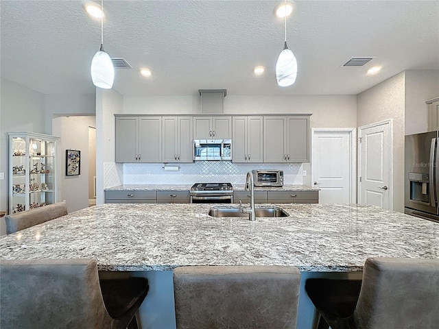 655 Conservation Blvd, Groveland, FL 34736 - kitchen with appliances with stainless steel finishes, gray cabinetry, a kitchen breakfast bar, and light stone countertops